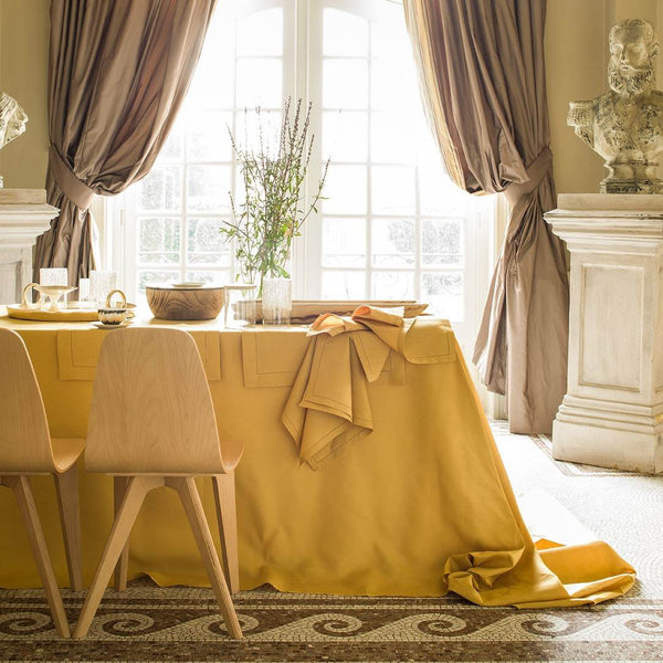 Dining room with a yellow tablecloth, chairs, and decorative elements.