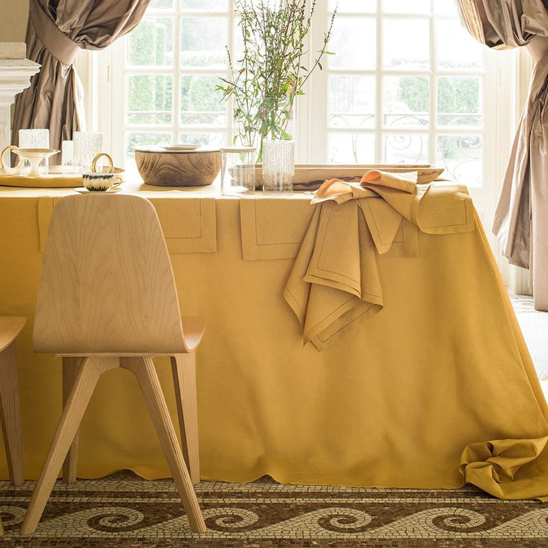 Dining room with a yellow tablecloth, wooden chair, and decorative elements.