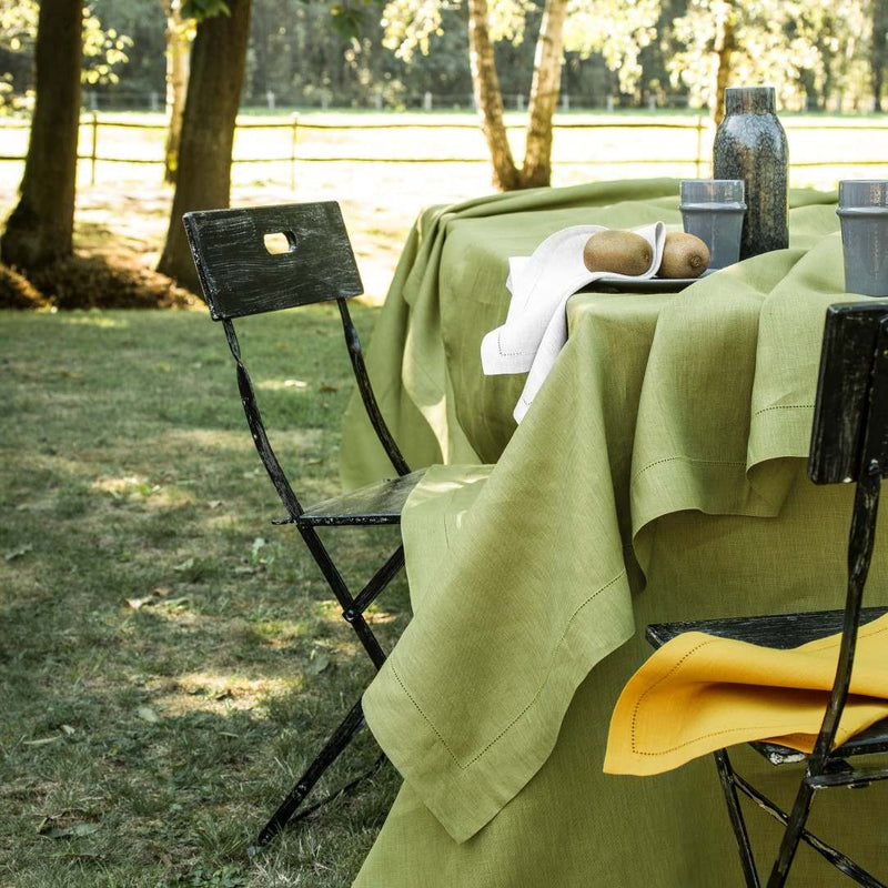 Green tablecloth on a table outdoors with chairs and a scenic background