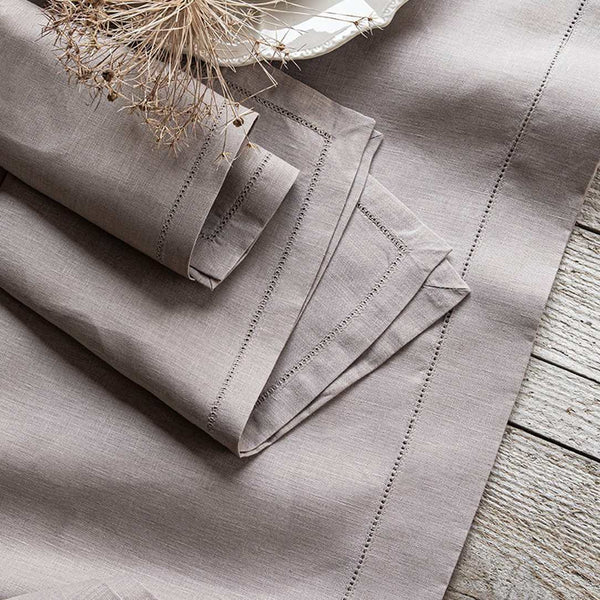 Folded beige fabric with embroidered details on a wooden surface
