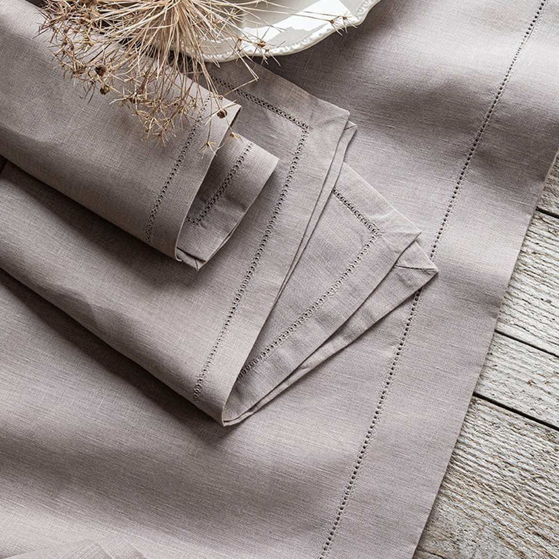 Folded beige fabric with embroidered details on a wooden surface