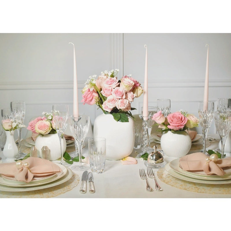 Elegant table setting with pink roses, white candles, and decorative vases.
