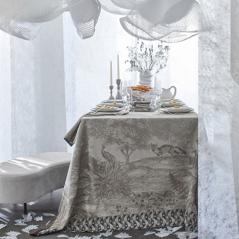 Elegant dining table setting with a decorative tablecloth featuring animal prints.