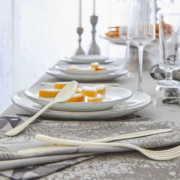Dining table setting with plates, cutlery, and glasses on a patterned tablecloth.