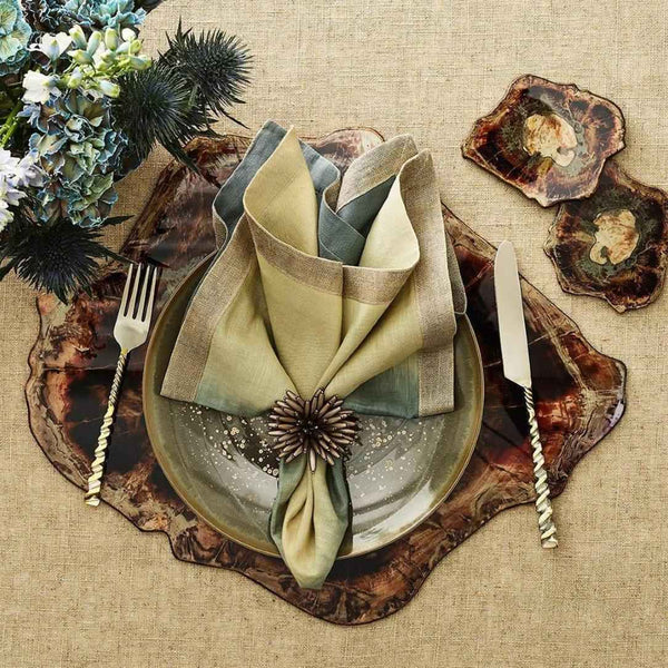 Decorative table setting with a green napkin, ceramic plates, and cutlery on a textured surface.