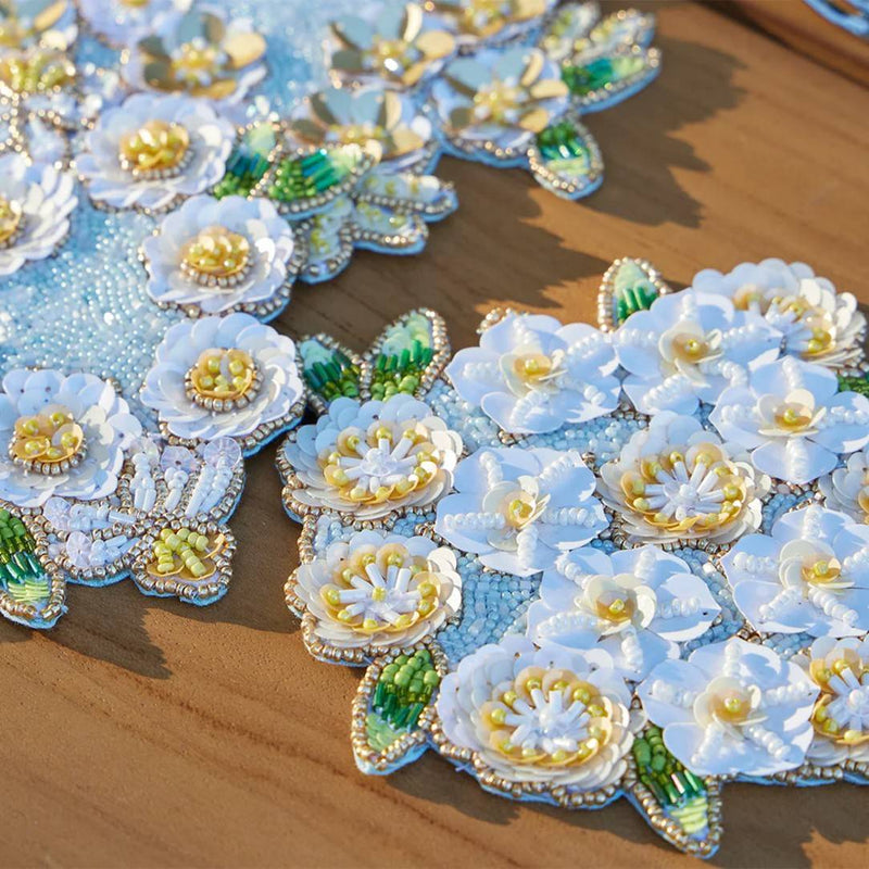 Decorative coaster flowers with beads and sequins on a wooden surface