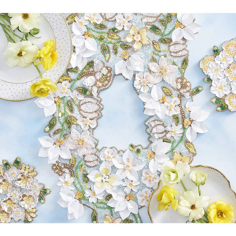 Decorative runner and coasters with floral patterns and embroidery on a light blue background