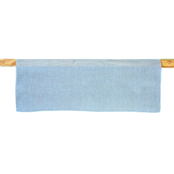 A light blue linen table runner is displayed on a wooden rod, showcasing its texture and color.