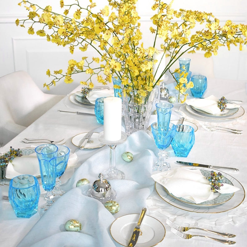 dining table decorated with yellow spray orchids and blue glasses