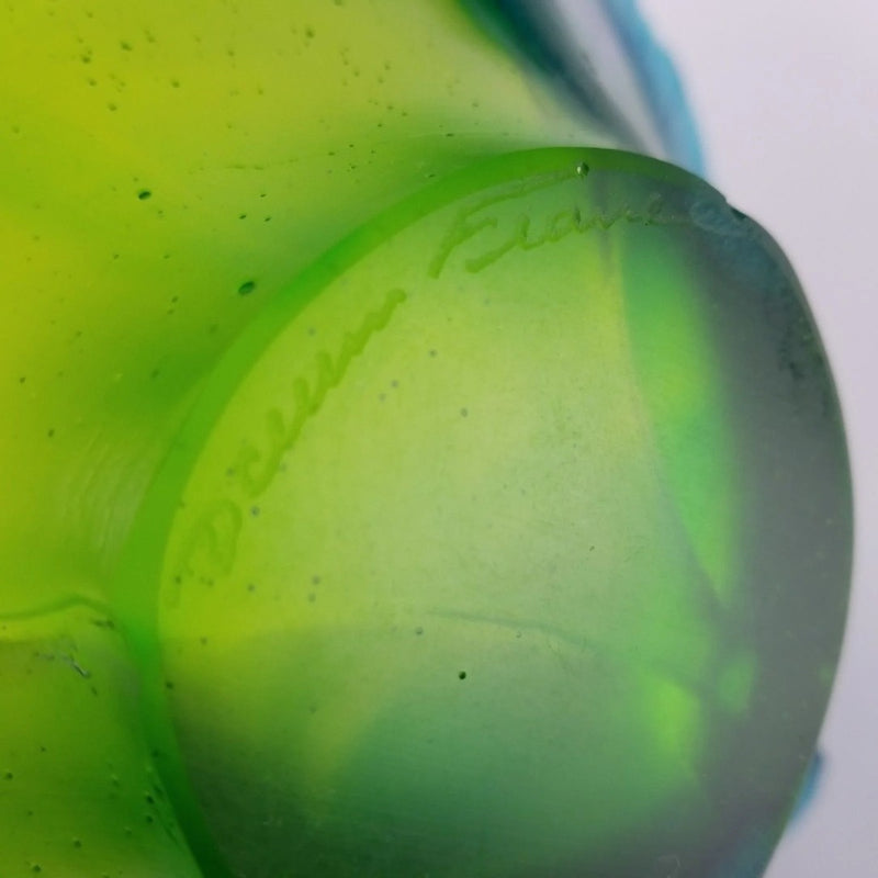 Close-up of a green crystal bowl from Daum with 'Bullseye' branding on a white background