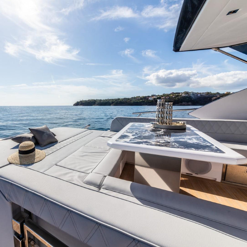 Yacht deck with Luxury glass carafe Marghe by Pinetti, table and cushions under a clear blue sky