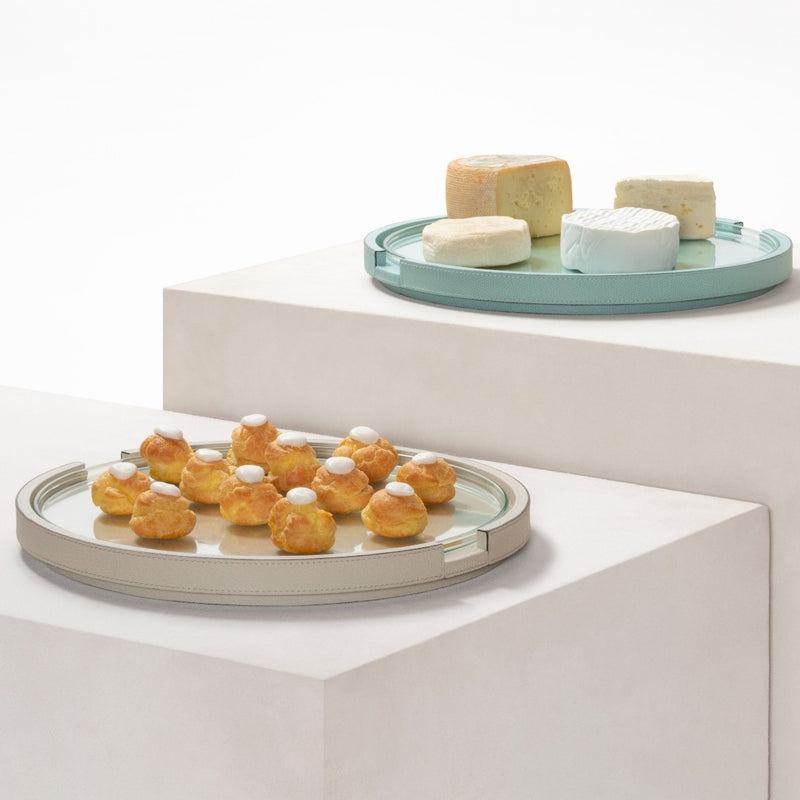 Round Gourmet serving tray by Giobagnara with removable glass top with pastries on a white surface with a smaller tray of cheese in the background