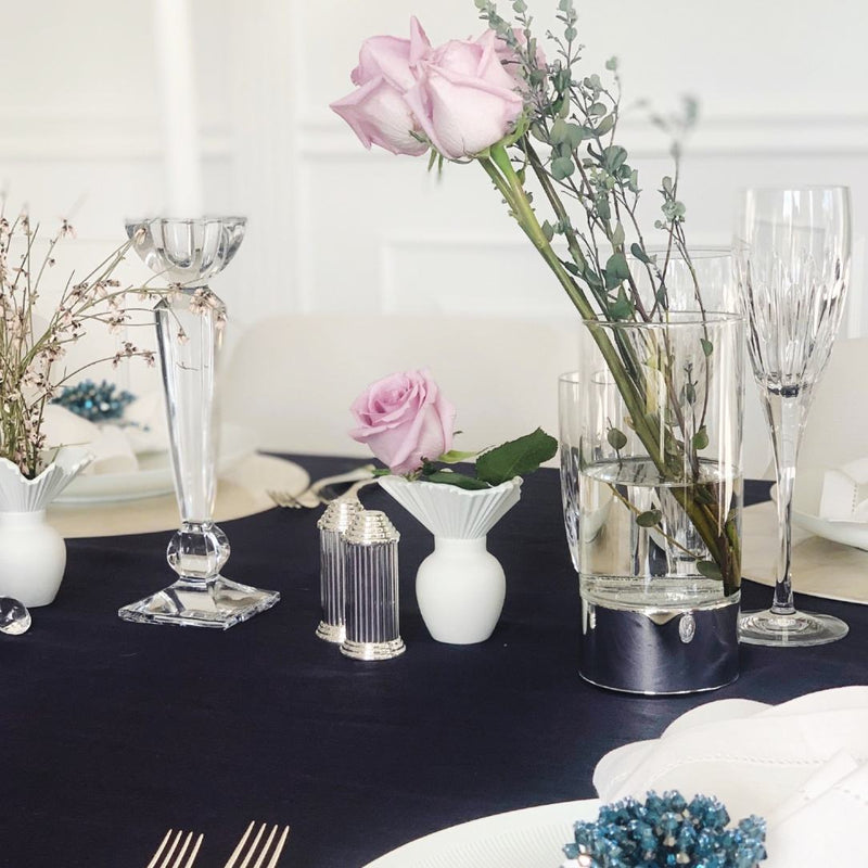 Decorative table setting with flowers, vases, and cutlery on a dark surface.