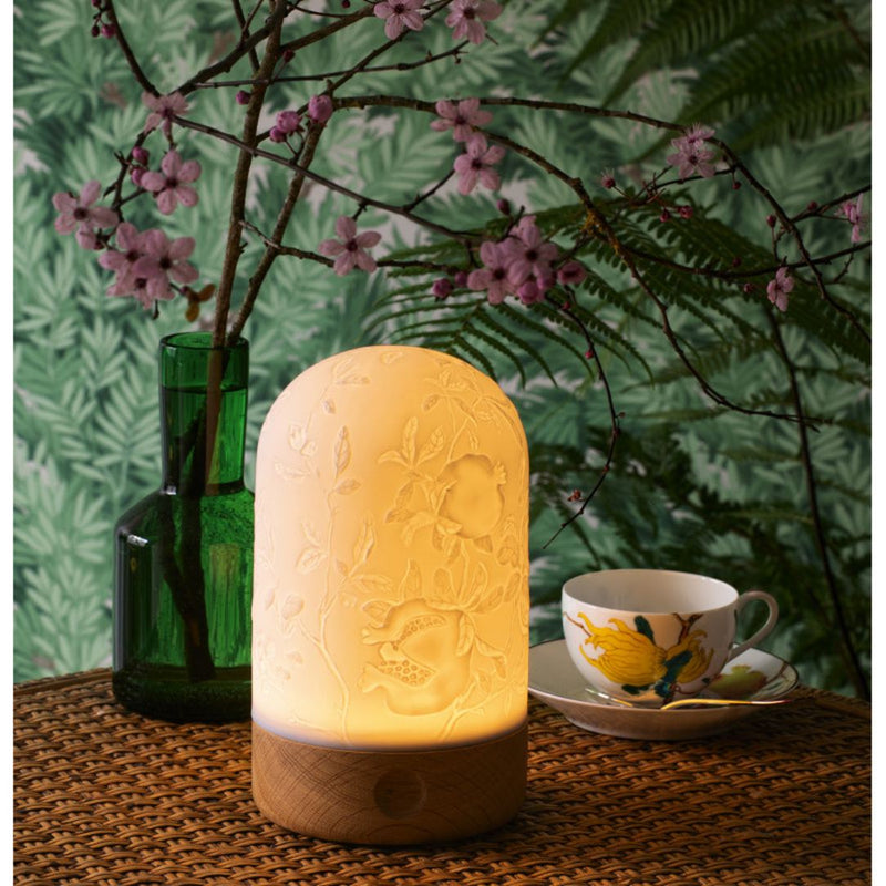 Decorative lamp on a table with a floral arrangement and teacup in the background