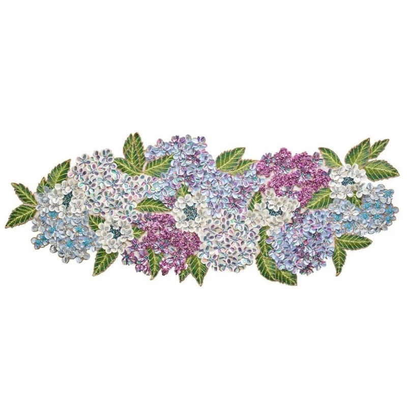 A decorative table runner featuring a floral pattern with hydrangea flowers in shades of blue, purple, and white, accented with green leaves.