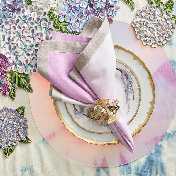 butterfly napkin in gold on a pink plate with pink napkin and beaded runner on the background