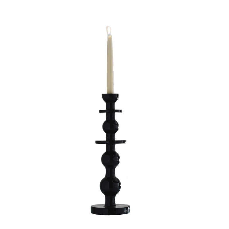 Black candle holder with a white candle on a white background