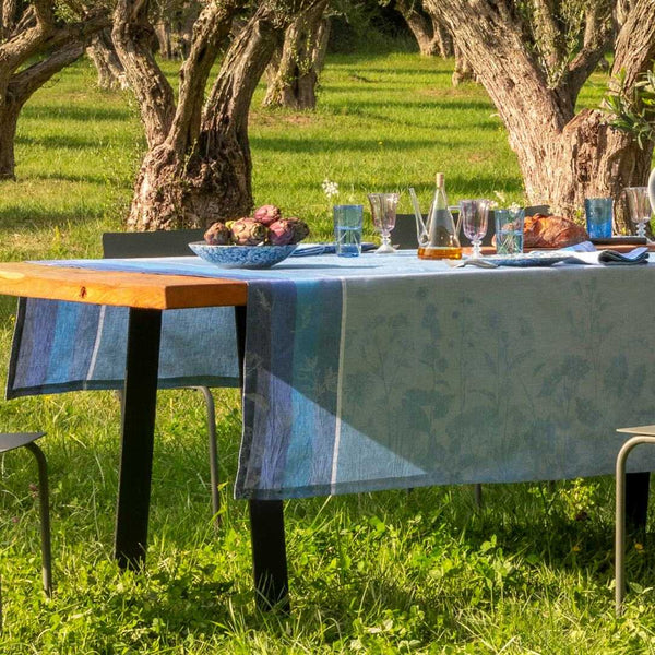 Dining table set with food and drinks in an outdoor setting with trees and grass.