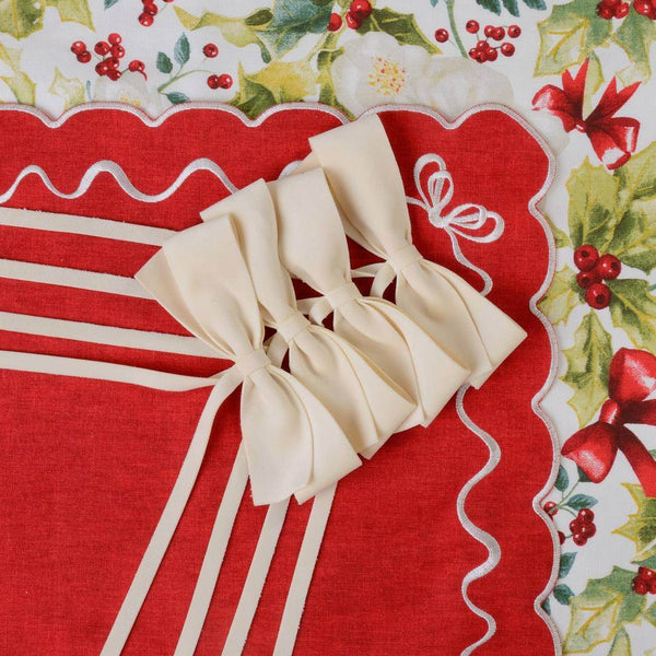Ivory velvet bows by Roseberry Home used as elegant napkin ties on a red Christmas table setting on a red fabric background with floral and berry pattern