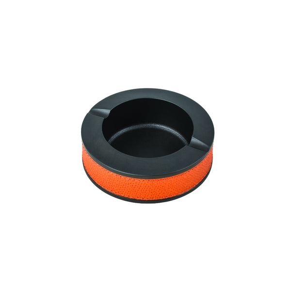A round orange ashtray with a black rim, crafted from metal with a leather lining.