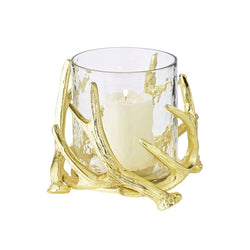 A gold-colored candle holder with a clear glass bowl and decorative steel deer antlers supporting a candle.