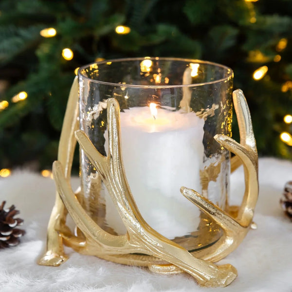Gold antler candle holder with a lit candle against a festive background