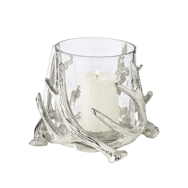 A silver candle holder with a clear glass bowl and decorative steel deer antlers supporting a candle.