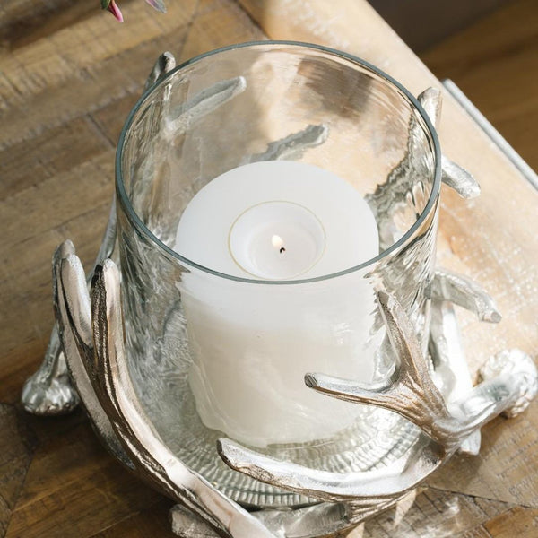 Candle in a glass holder with decorative metal base on a wooden surface