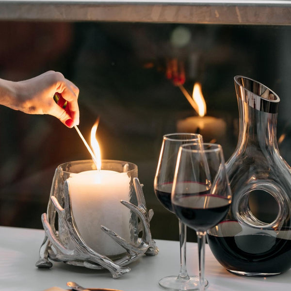 styled lit candle with Kingston hurricane candle holder by Edzard with steel deer antlers and clear glass bowl
