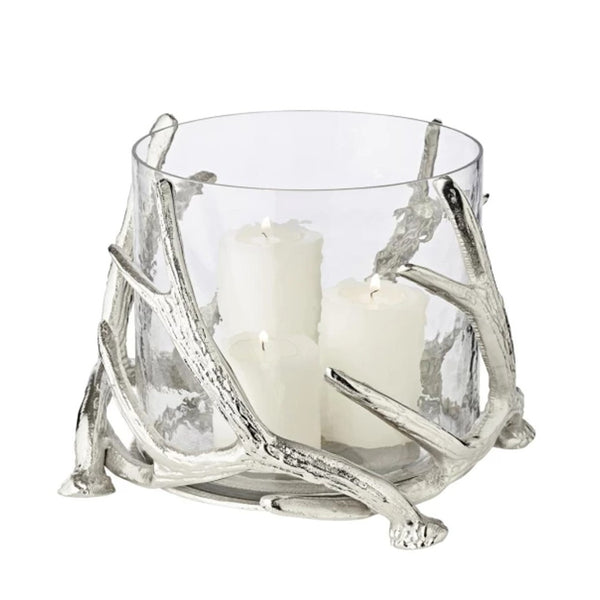 A silver candle holder with deer antlers as a decorative element, containing three candles.
