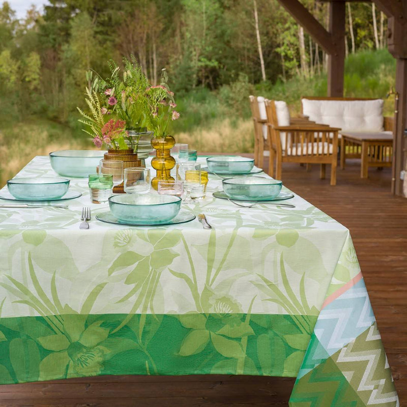 Outdoor table setting with a floral-patterned tablecloth on a wooden deck.