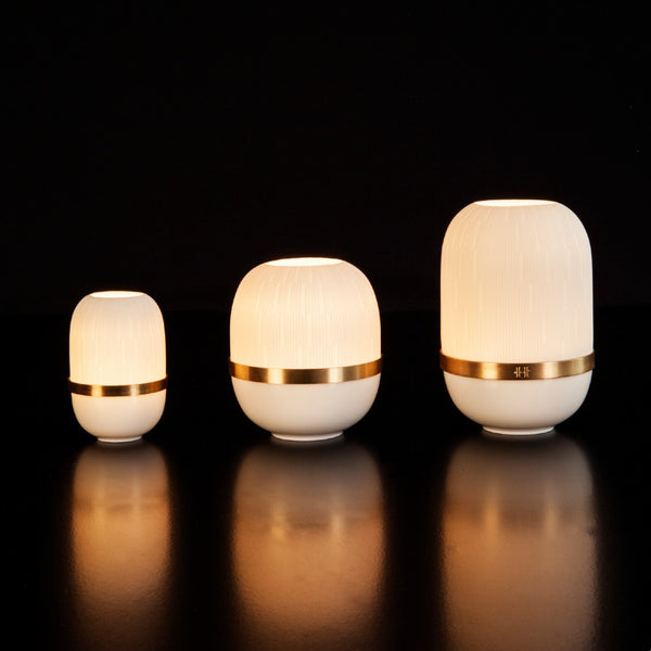 Three white cylindrical lamps with gold bands on a black background