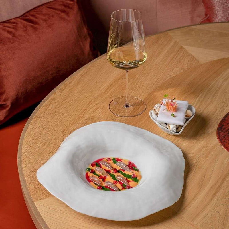 Glass of white wine on a wooden table with a Set of 2 large deep dinner plates white No7 Indulge by Sarah-Linda porcelain and a small bowl.
