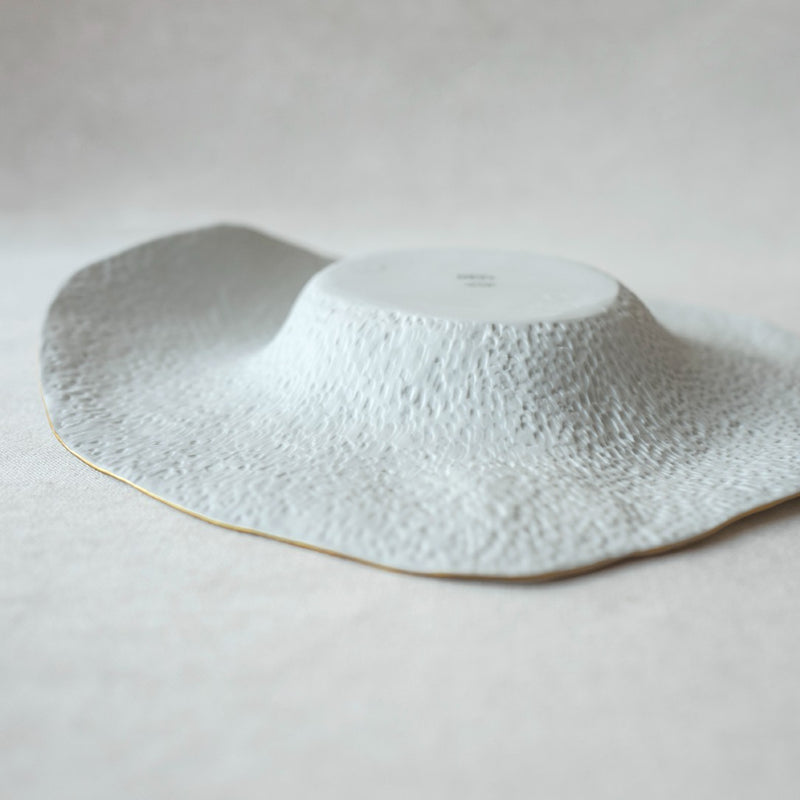 the back of the large deep plate white with golden rim No7 Indulge porcelain on a light gray background