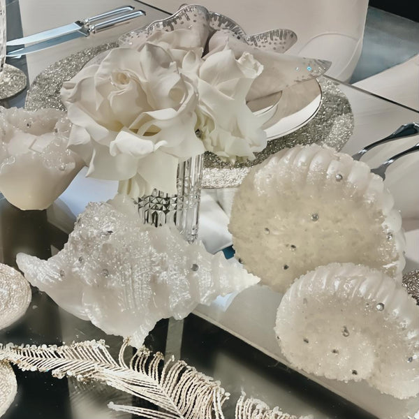 Styled table with White conch shell candle with silver glitter detailing, elegant coastal-inspired decoration by Amiramour.