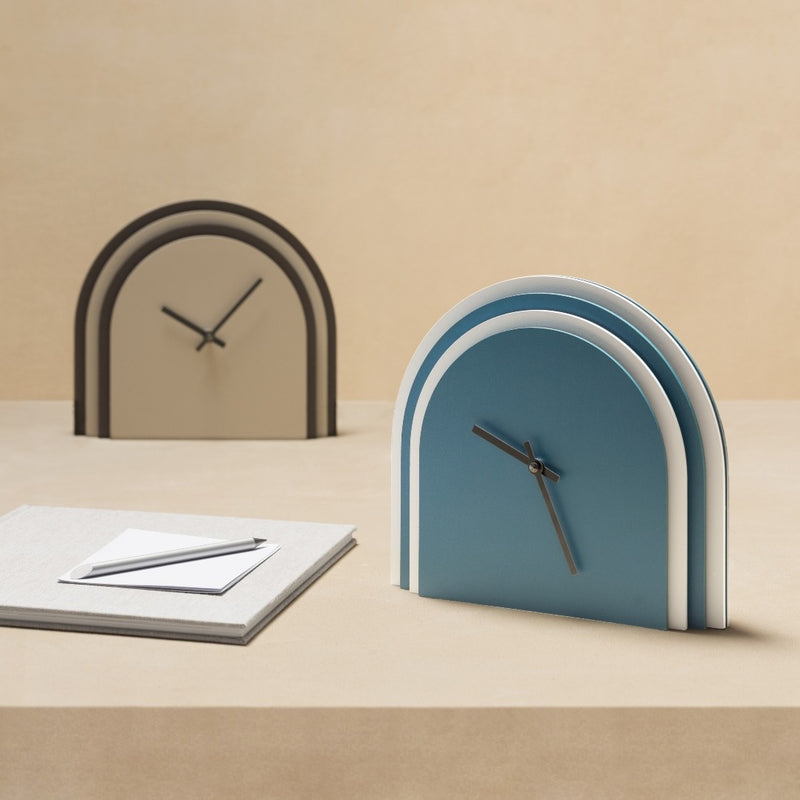 Two unique clock designs on a beige surface with a neutral background