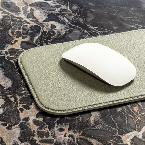 White mouse on a green leather mouse pad with a marble surface background
