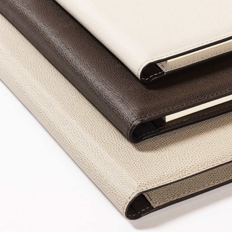 Stacked close-up Giobagnara leather notepad holders with suede lining, pen holder, and ivory paper