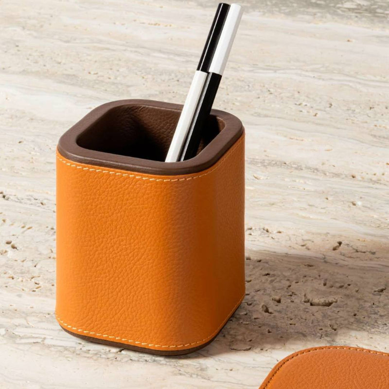 Orange pen holder with a pen on a light wooden surface