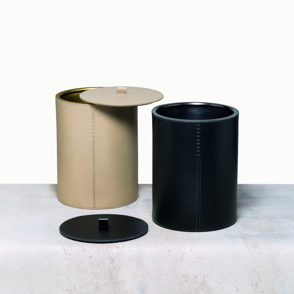 Two cylindrical wastepaper bins, one beige and one black, on a light gray surface with a white background.