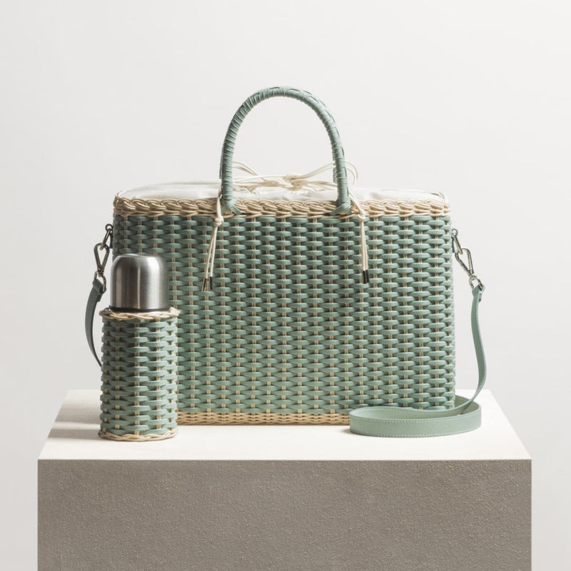 Woven green handbag with matching bottle holder on a white background