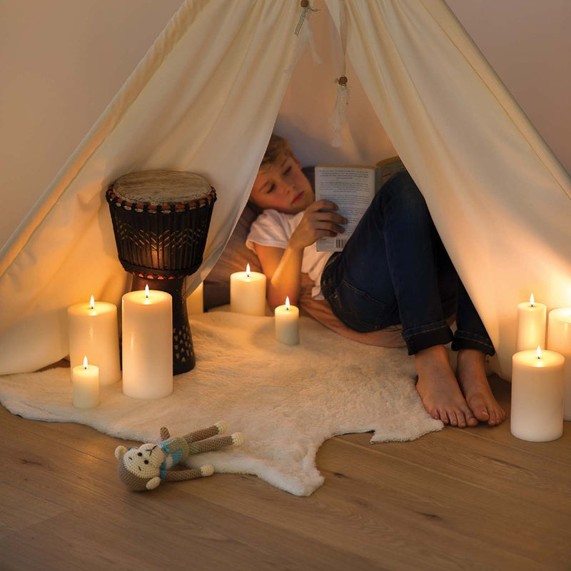 styled nook with child reading book and LED pillar candle 25cm in Nordic White by Uyuni Lighting, extra tall with melted edge