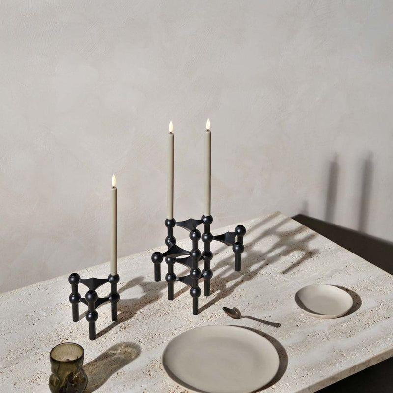 Decorative black candle holder with candles on a textured surface