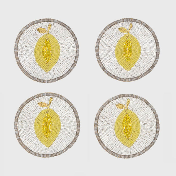 Four round coasters with lemon design on a white background