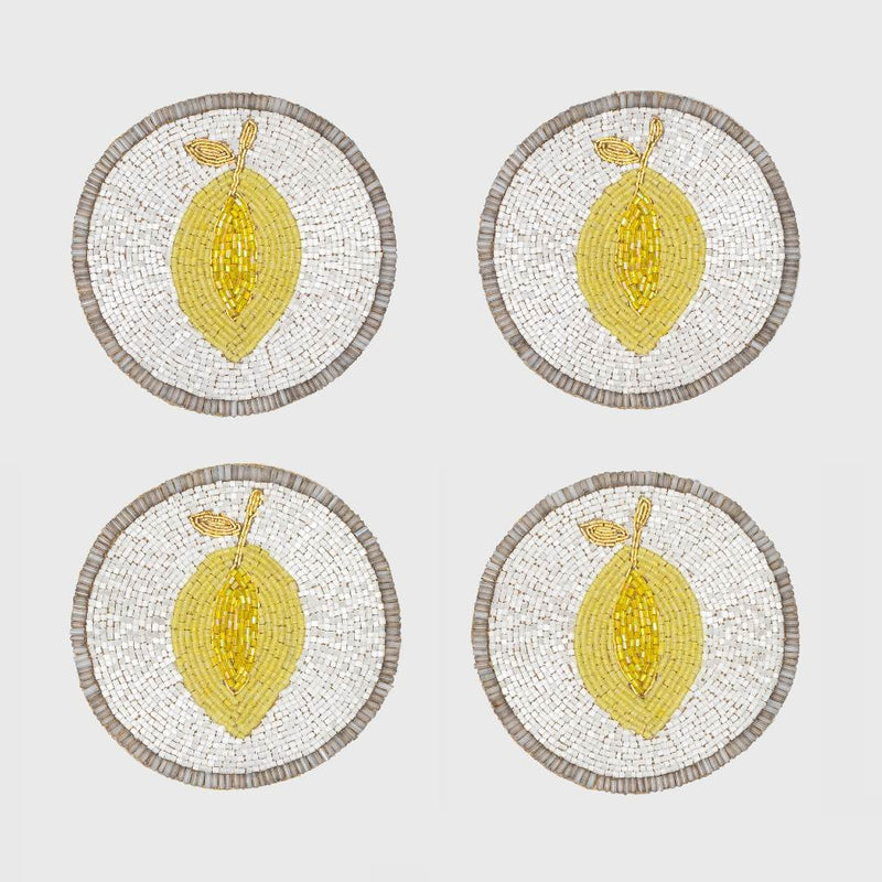 Four round coasters with lemon design on a white background