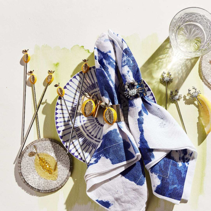 Blue and white patterned napkin with lemon coaster and decorative items on a light yellow background