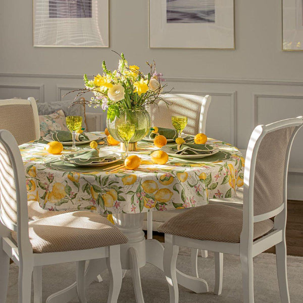 Dining table set with a floral tablecloth, lemon decorations, and yellow flowers.