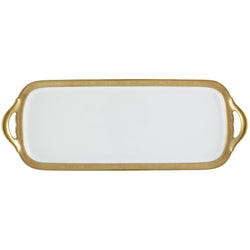 A white porcelain long cake serving plate with a gold Renaissance style border, inlaid with fine gold details, held by a gold-colored metal handle.