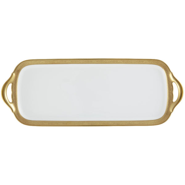 A white porcelain long cake serving plate with a gold Renaissance style border, inlaid with fine gold details, held by a gold-colored metal handle.