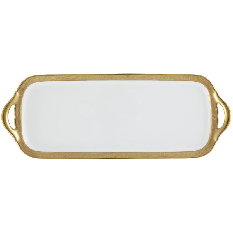 A white porcelain long cake serving plate with a gold Renaissance style border, inlaid with fine gold details, held by a gold-colored metal handle.